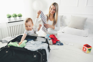 Travelling with kids. Happy mother with her child packing clothes for their holiday